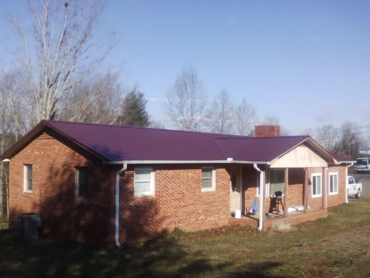 Burgundy metal roof on a brick ranch home with a new addition in Paola