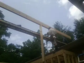 Carpenter setting a ridge beam over a new addition frame — Ice Dam Removal by Roofing Brothers in Paola