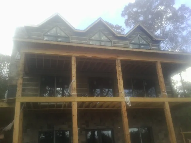 Dormers and porch framing on a large log home under construction — Roof Coating work by our crew in Paola