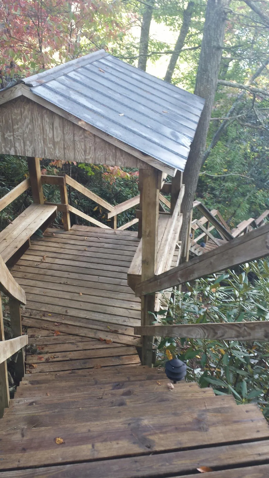 Metal roofed shelter over wooden steps on a wooded walkway — Skylight Repair & Installation work by our crew in Paola