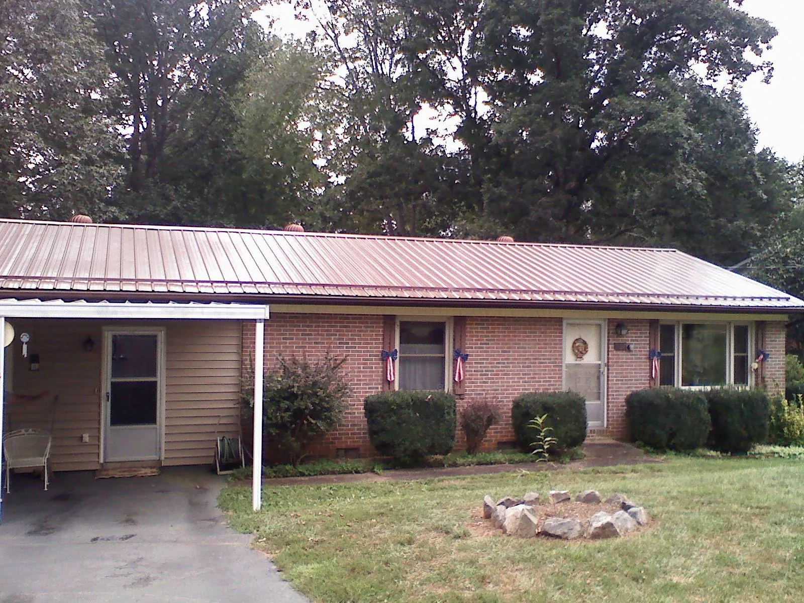 Bronze metal roof and carport on a brick ranch home — Roof Repair work by our crew in Paola