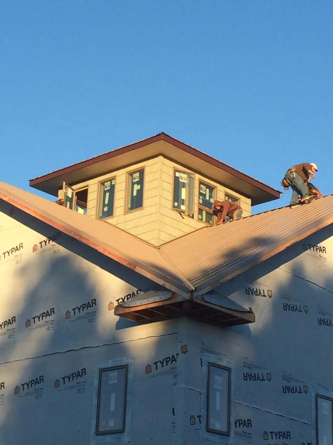Roofers working around a rooftop cupola on a new metal roof at sunset — Roof Waterproofing in Paola by Roofing Brothers